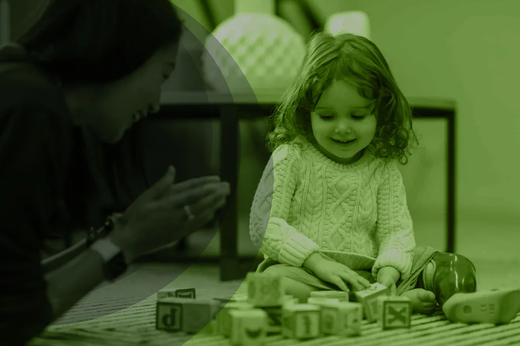 A child playing with wooden blocks while an adult watches